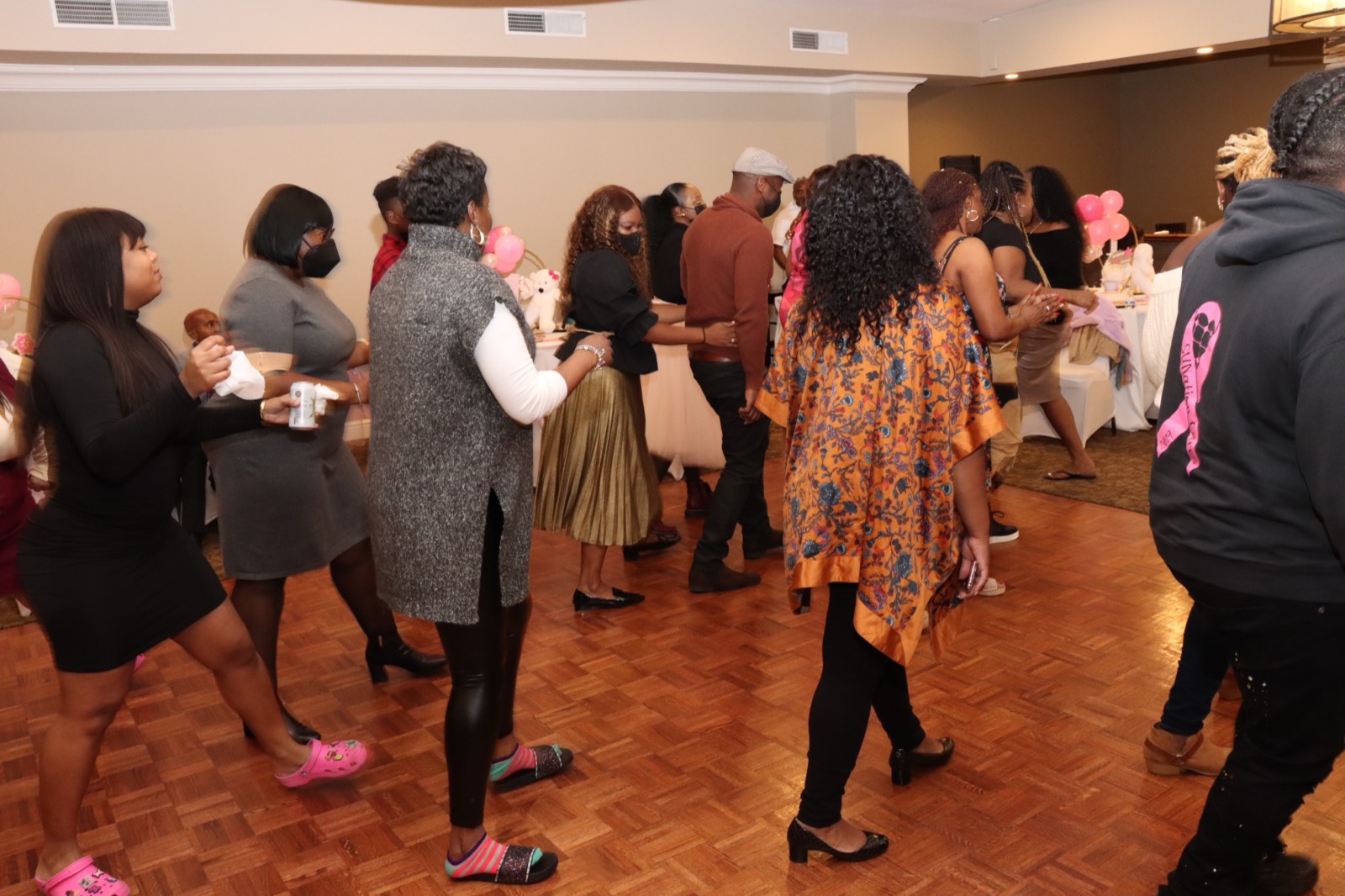 Guests gathering and dancing at the pink-themed first-birthday reception.