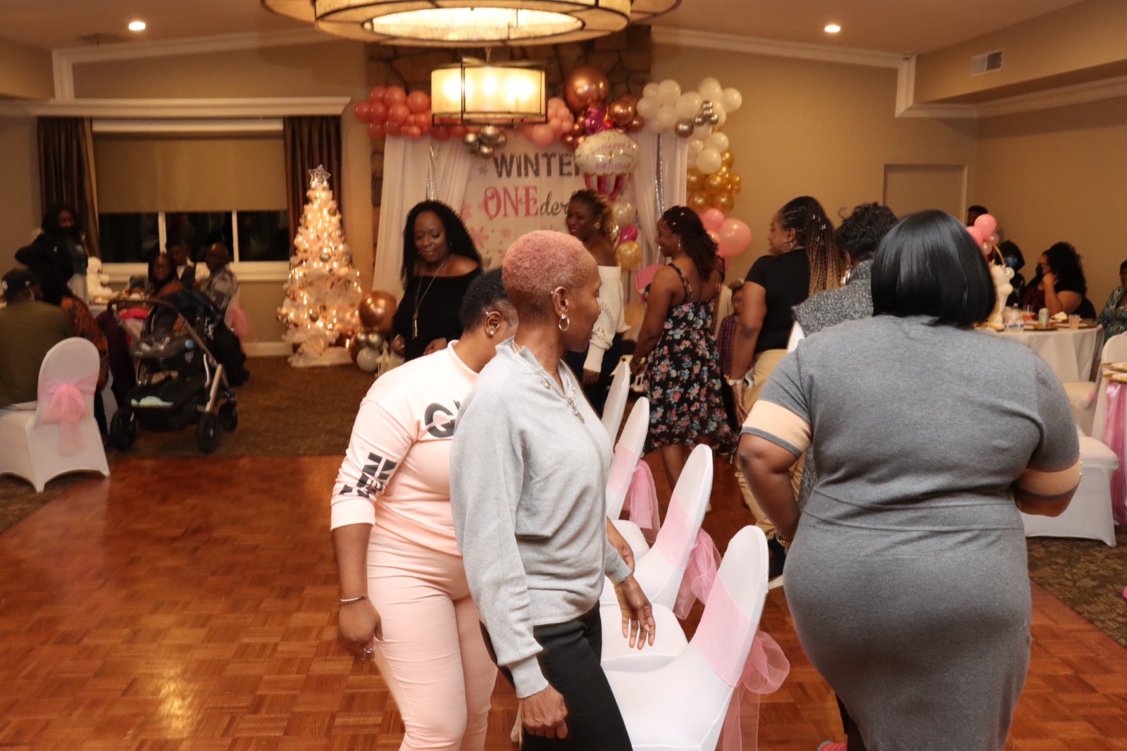 Guests dancing and mingling at the pink-and-gold first-birthday celebration.