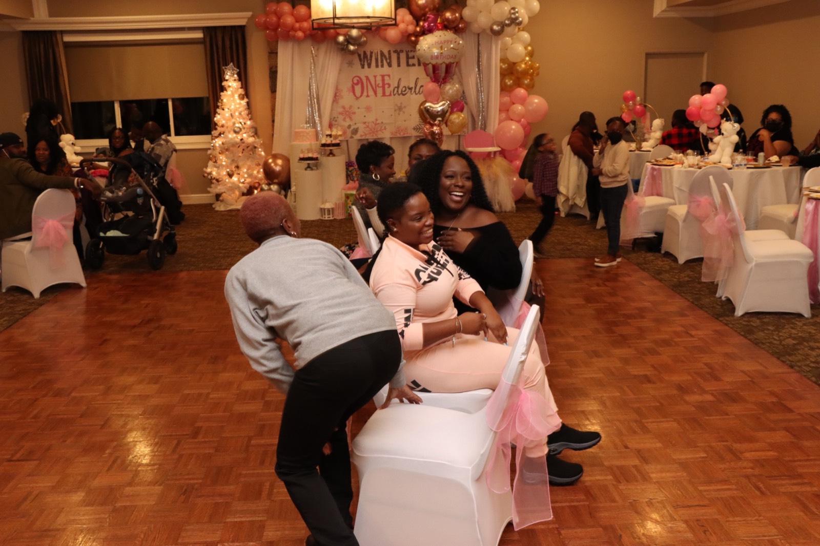 Guests laughing and celebrating in front of the pink 'Winter ONEderland' backdrop.