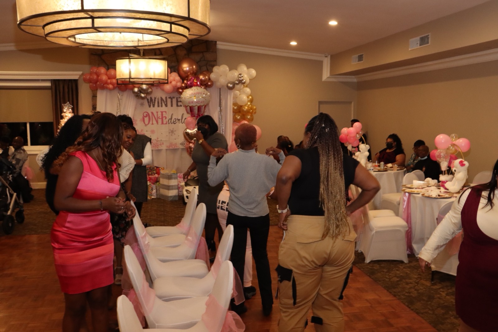 Guests mingling on the dance floor at the pink-and-gold first-birthday reception.