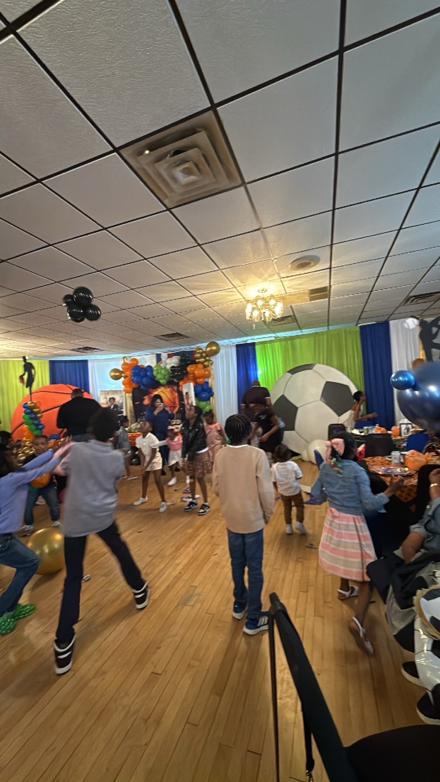 Children dancing at the sports-themed tenth-birthday celebration with a giant soccer-ball decoration.
